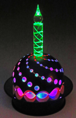 Sycamore and Perspex. 250 mm high + base. 150 mm diameter wood dome. 70 Perspex dowels, 25 mm diameter Perspex carved central candle and 3 individual LED's inside dome that have fixed and flashing modes. Mounted on rotating mirrored display turntable. Ref 11.05