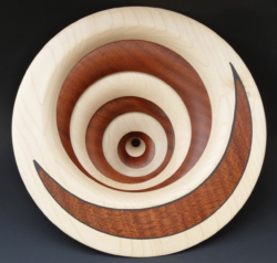 "Sycamore and sapele. 250 mm diameter. 7 discs of alternating light & dark wood. Off-centre holes. Ref 12.03
"